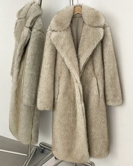 Two beige faux fur coats hanging on a rack against a white wall.