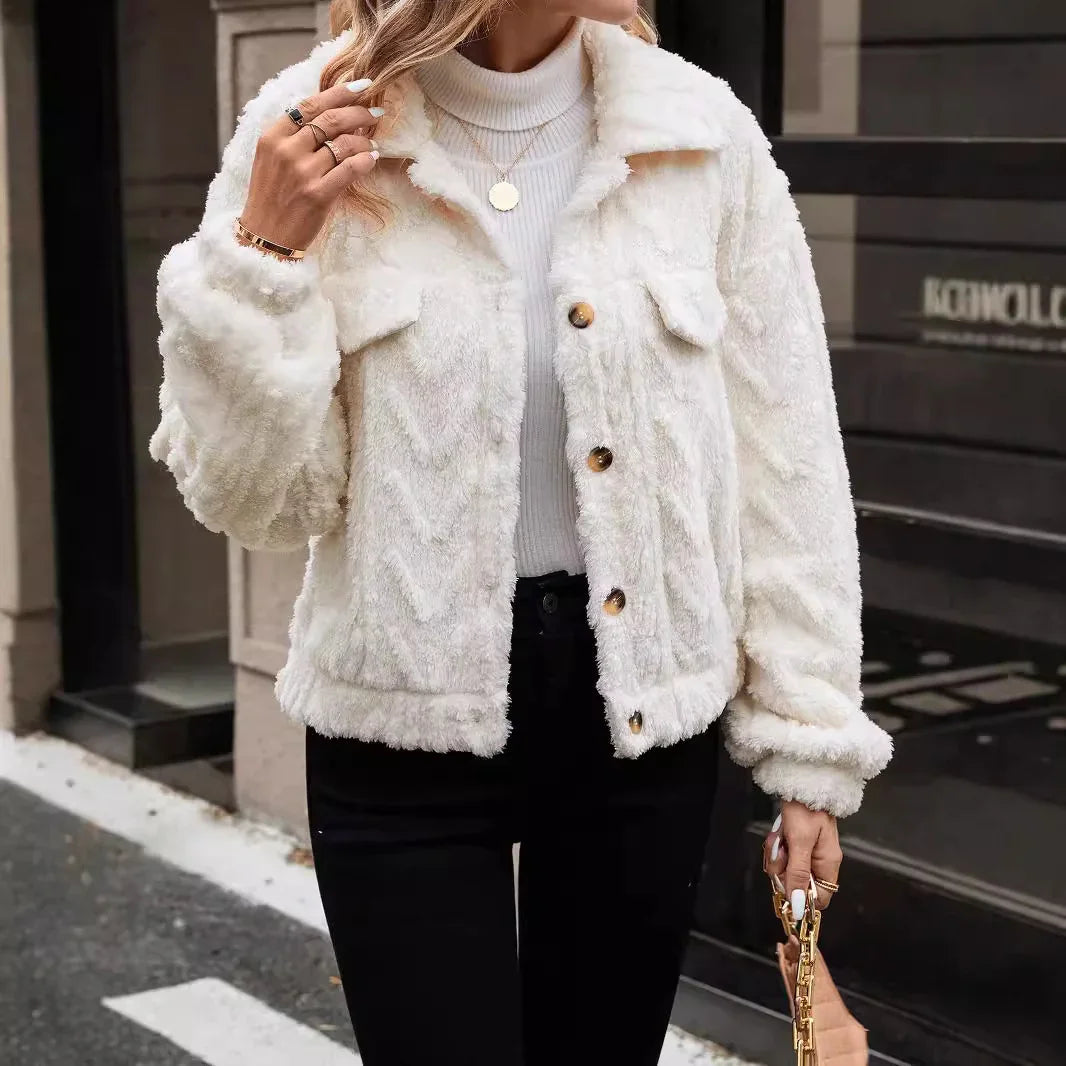 Person wearing a white fluffy jacket with brown buttons in an urban setting