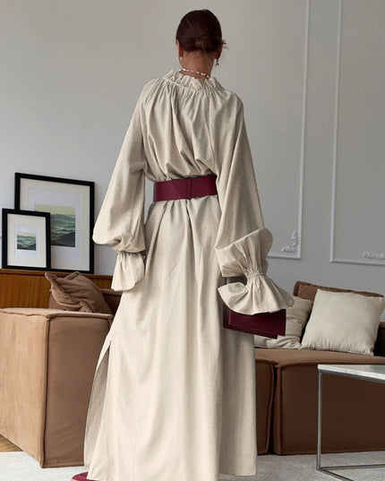 Woman wearing a beige dress with maroon accents in a living room setting