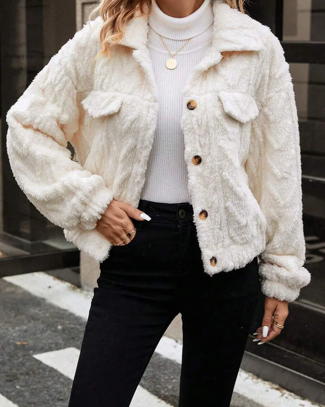 Person wearing a white fluffy jacket with brown buttons on a street.
