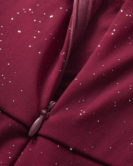 Close-up of a maroon fabric with a zipper and small white specks.