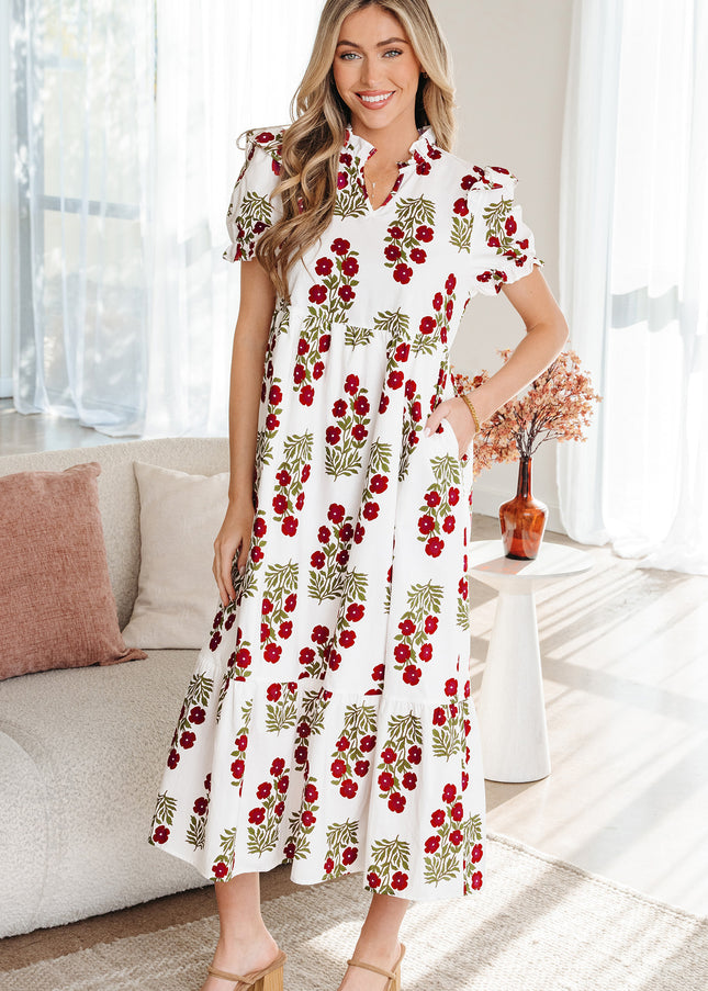Woman wearing a white dress with red floral pattern in a bright living room.