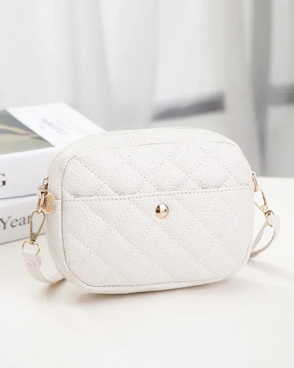 White quilted handbag with gold chain strap on a light surface