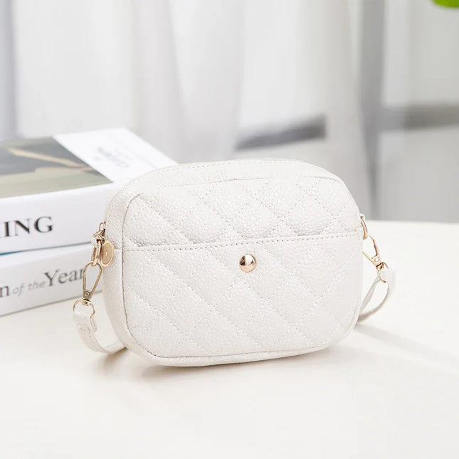 White quilted handbag with gold chain strap on a light surface