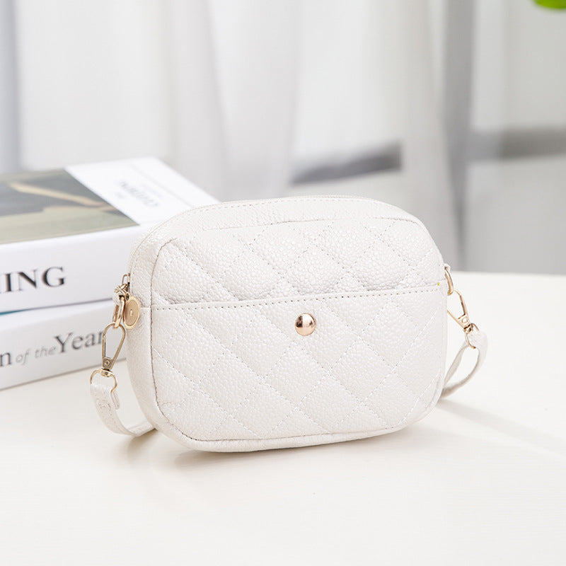 White quilted handbag with gold chain strap on a light surface