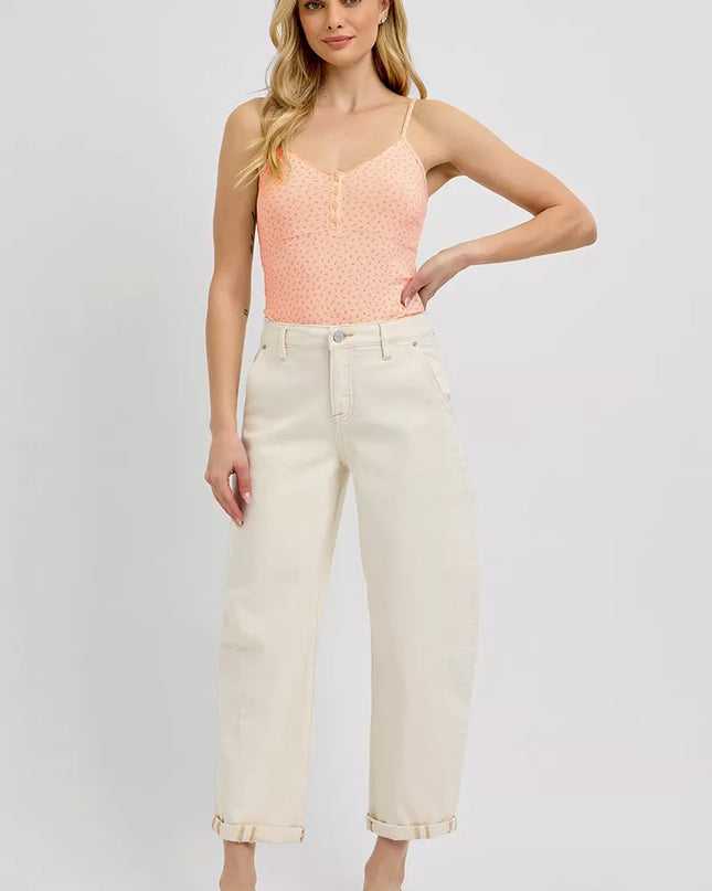 Woman wearing a pink sleeveless top and white pants on a plain background