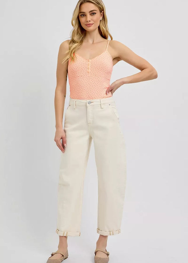 Woman wearing a pink sleeveless top and white pants on a plain background