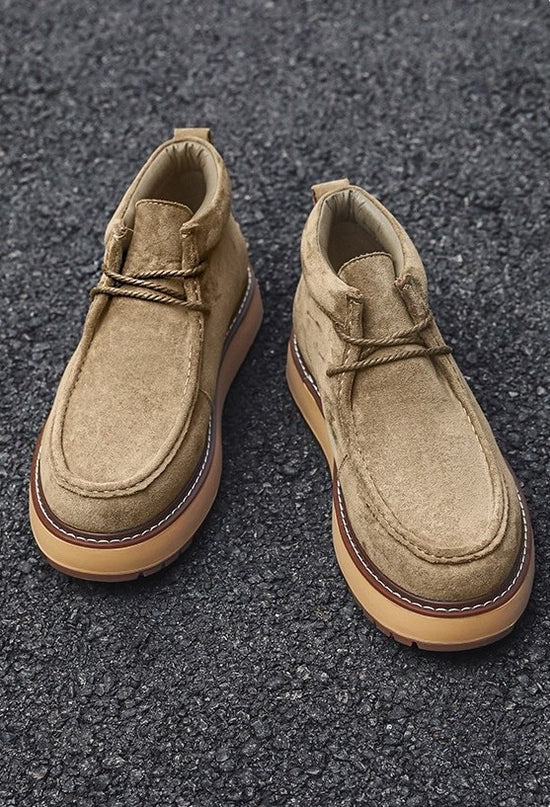 Pair of tan suede shoes on a dark textured surface