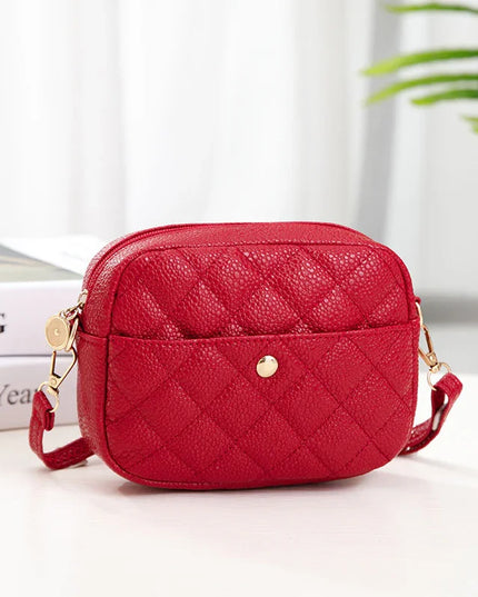 Red quilted handbag on a white surface with a blurred background