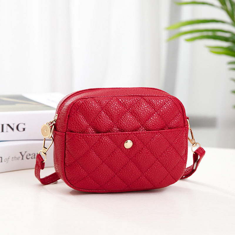 Red quilted handbag on a white surface with a blurred background