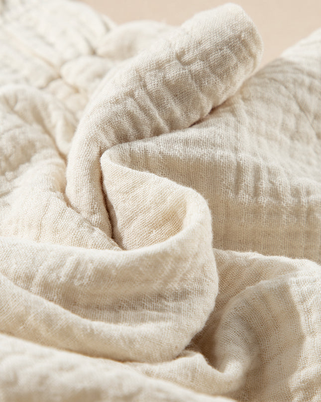 Close-up of a textured beige fabric with a soft, warm tone.