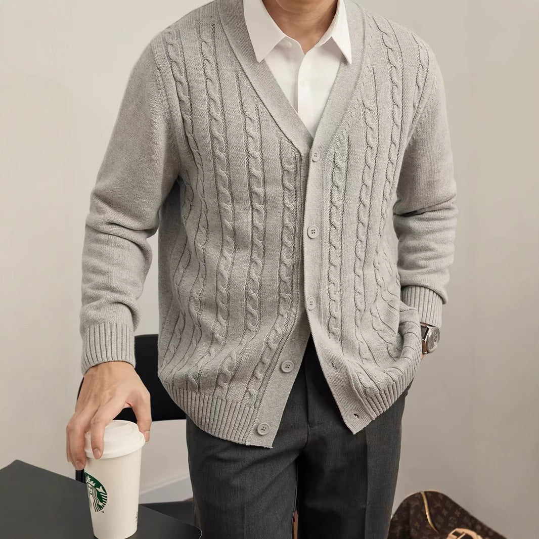 Person wearing a gray cable knit cardigan holding a Starbucks cup.