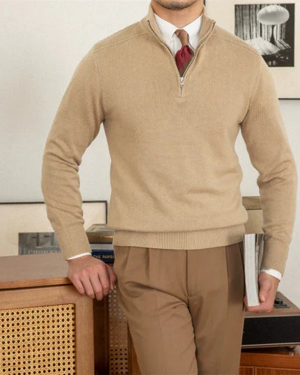 Man wearing a beige sweater and pants in an indoor setting