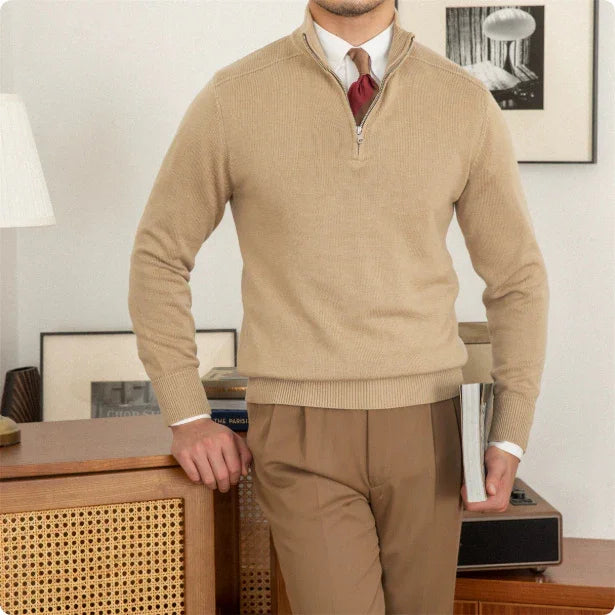 Man wearing a beige sweater and pants in an indoor setting