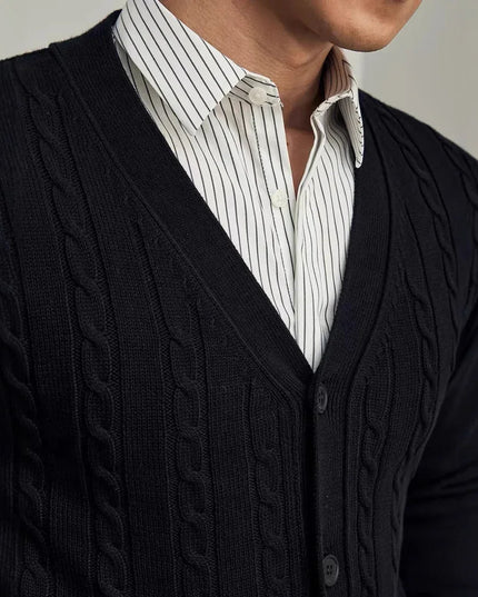 Person wearing a black cable knit cardigan over a white shirt with thin black stripes.