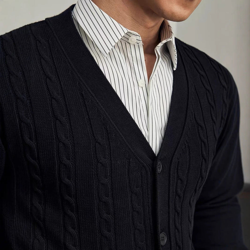 Person wearing a black cable knit cardigan over a white shirt with thin black stripes.