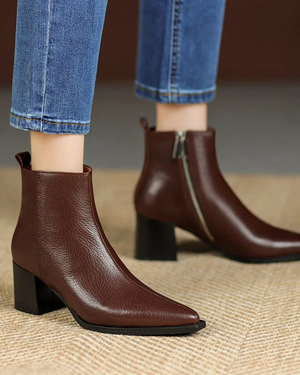 Brown ankle boots worn with blue jeans on a textured surface