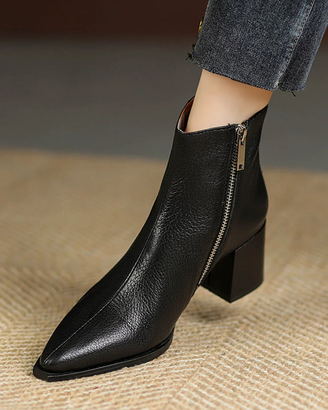 Black leather ankle boot with a zipper on a textured surface