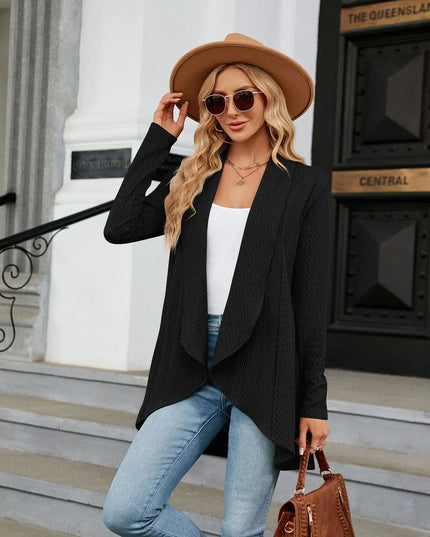Woman in stylish outfit with black blazer, white top, blue jeans, and brown hat standing on steps.