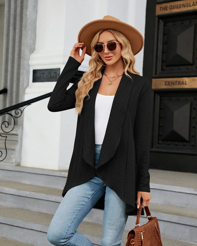 Woman in stylish outfit with black blazer, white top, blue jeans, and brown hat standing on steps.