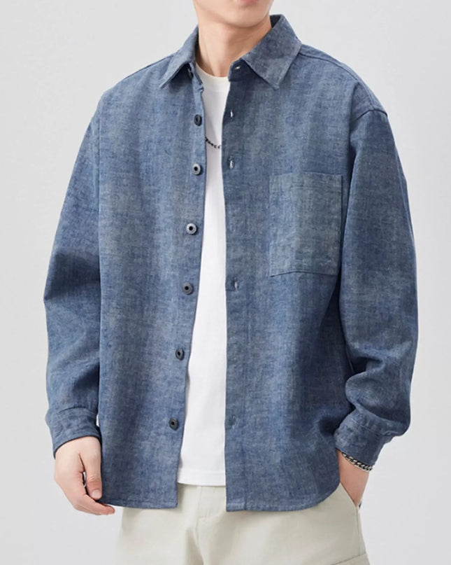 Person wearing a blue denim shirt over a white t-shirt on a light gray background