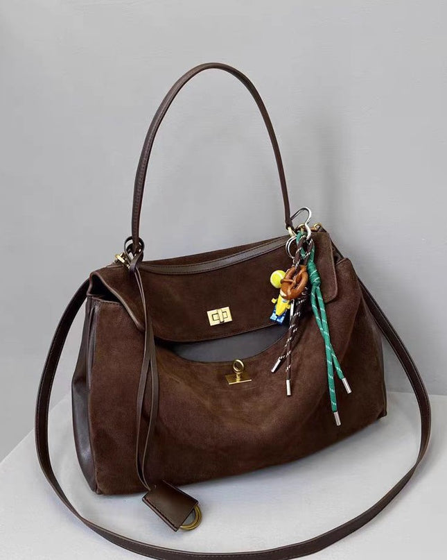 Brown leather handbag with keychain on a light gray background