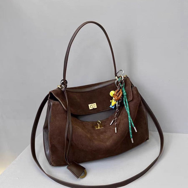 Brown leather handbag with keychain on a light gray background